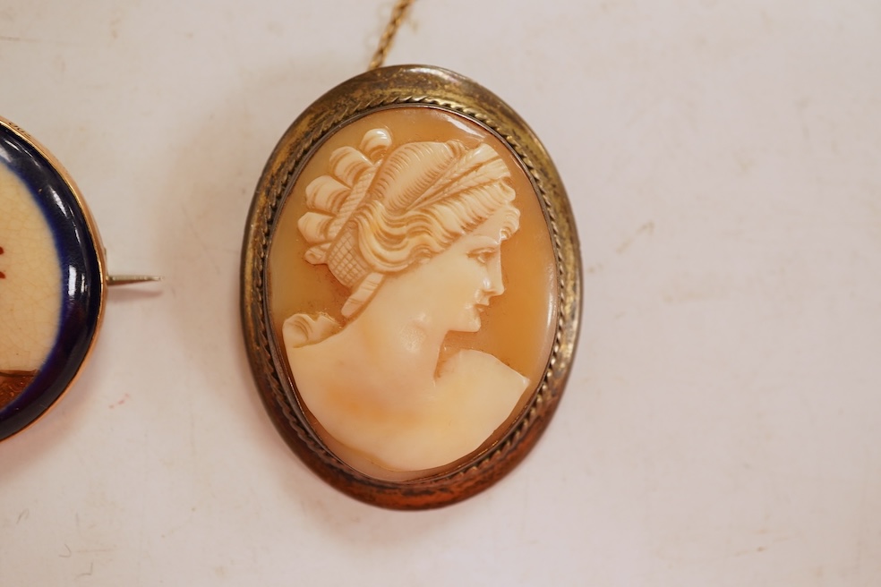 A Satsuma brooch, set with a circular Satsuma plaque depicting an oiran with gilded hair ornaments, mounted in 9ct gold, 3.3cm diameter, British hallmarks; together with an oval shell cameo brooch depicting a classical w